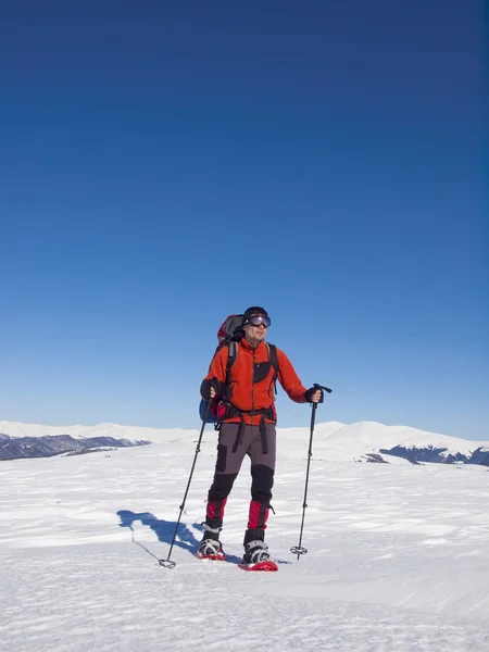 El hombre en raquetas de nieve en las montañas . — Foto de Stock