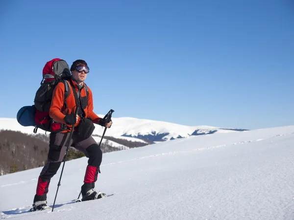 El hombre en raquetas de nieve en las montañas . — Foto de Stock