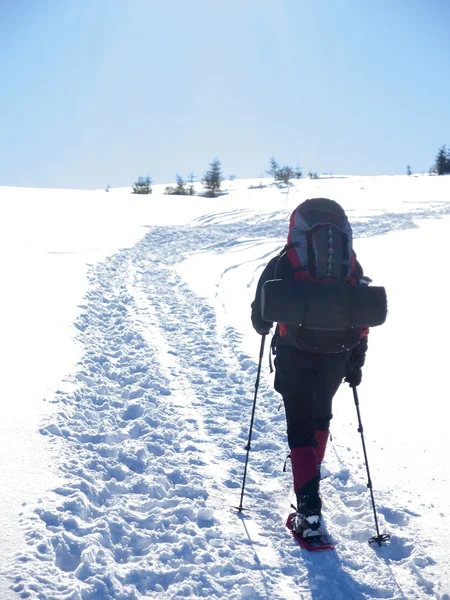 De man in sneeuwschoenen in de bergen. — Stockfoto