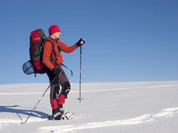 The man in snowshoes in the mountains indicates the direction. — Stock Photo, Image