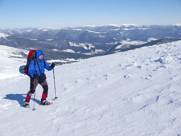 El hombre en raquetas de nieve en las montañas . — Foto de Stock