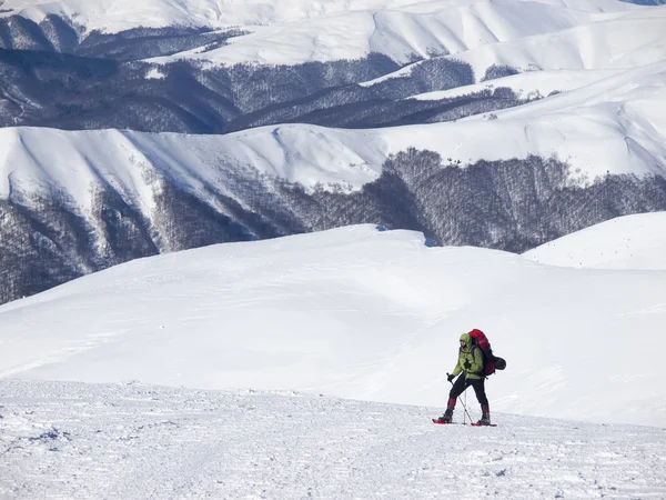 El hombre en raquetas de nieve en las montañas . — Foto de Stock