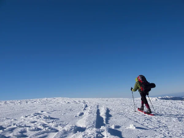 Mannen i snöskor i bergen. — Stockfoto