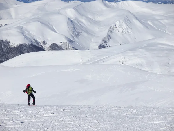 El hombre en raquetas de nieve en las montañas . — Foto de Stock