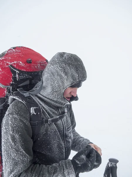 Sneeuw bedekte man met een rugzak in een dikke mist. — Stockfoto