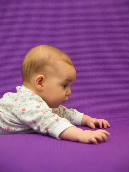 Baby op een paarse achtergrond. — Stockfoto