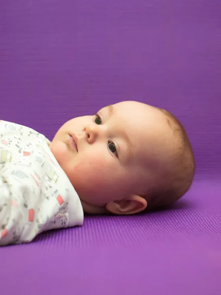 Spedbarn med lilla bakgrunn . – stockfoto