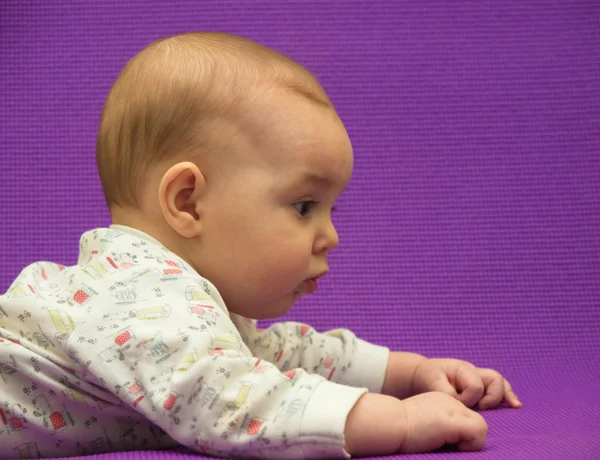 Baby op een paarse achtergrond. — Stockfoto