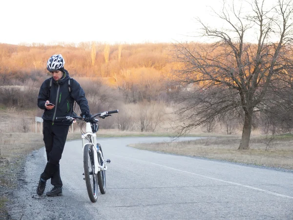 Homme à vélo debout sur la route et regardant le téléphone . — Photo