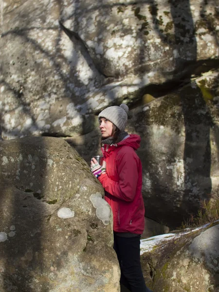 Das Mädchen mit dem Becher steht neben den Steinen. — Stockfoto
