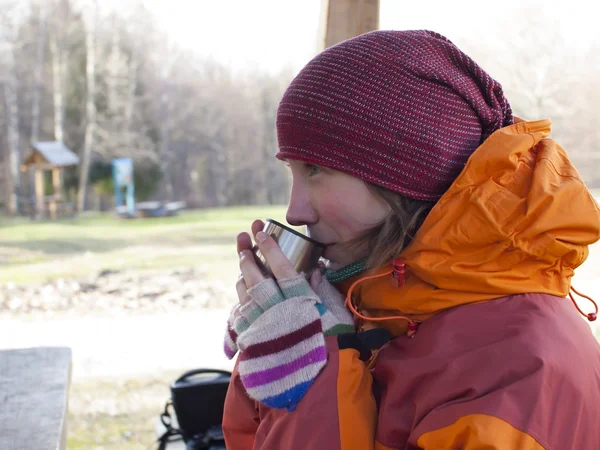 Das Mädchen sitzt an einem Tisch und trinkt aus einer Tasse. — Stockfoto