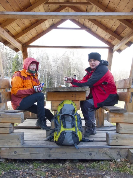 Touristen sitzen in einem hölzernen Pavillon am Tisch und trinken aus — Stockfoto