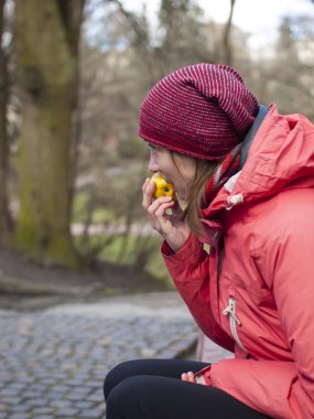 Genç bir kız bir elma yiyor.