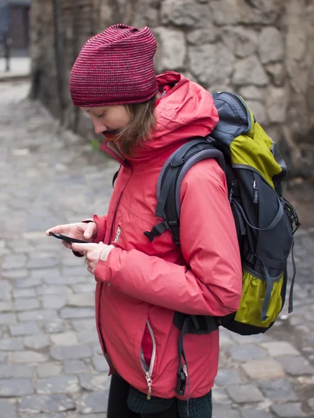 Девушка с рюкзаком смотрит в телефон . — стоковое фото