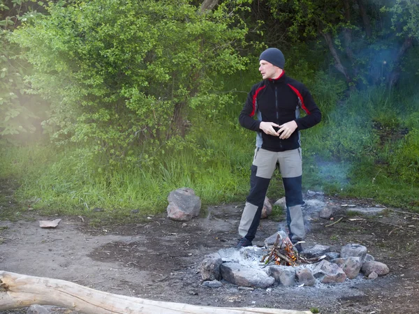 Un hombre se para cerca de un fuego . — Foto de Stock