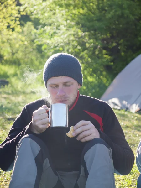 Un hombre bebiendo de una taza y comiendo galletas . — Foto de Stock