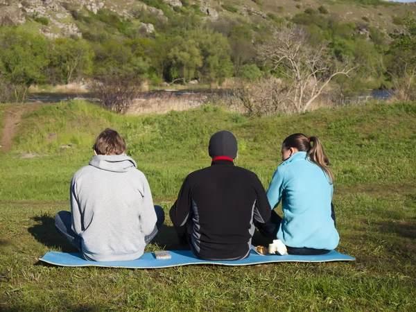 Tre vänner sitter i naturen. — Stockfoto