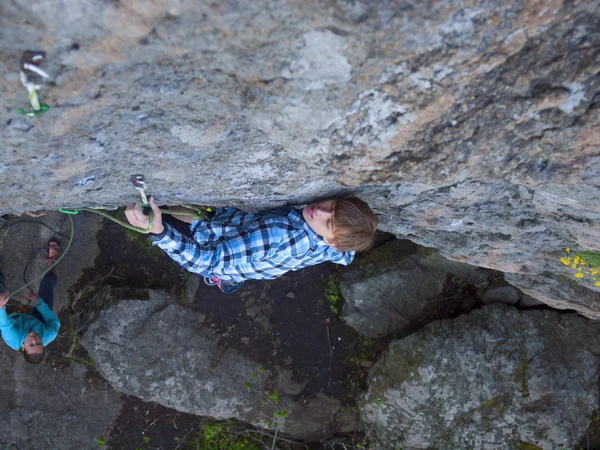 Schöner Mann im karierten Hemd klettert auf den Felsen. — Stockfoto