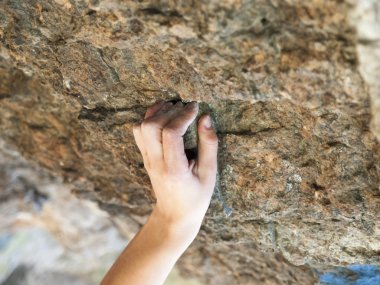 Kayanın üzerinde elini tutar.
