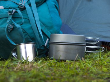 Cookware for camping is on the grass on the background of a back clipart