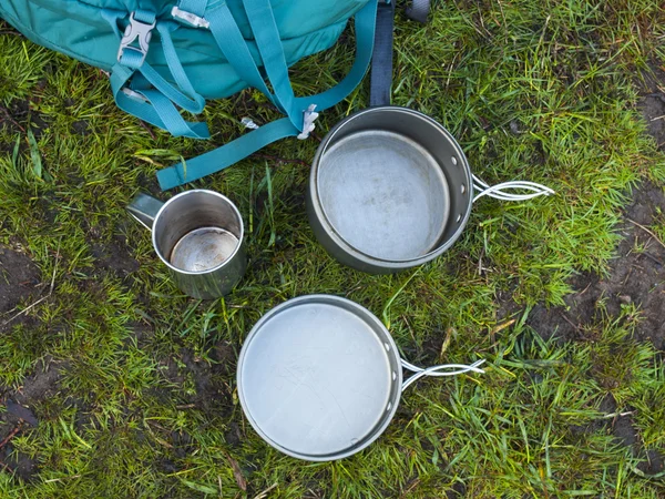 Os utensílios de cozinha para acampar estão na grama no fundo de umas costas — Fotografia de Stock