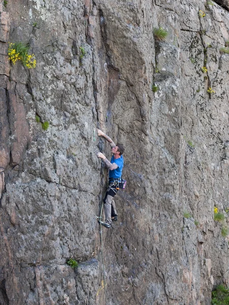 Mooie man klimt een hoge berg. — Stockfoto