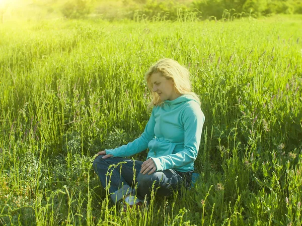 Chica sentada en un campo en la hierba verde . — Foto de Stock