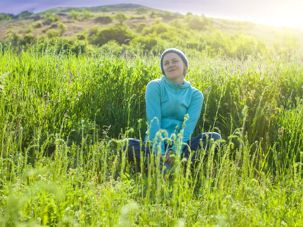 Retrato de uma jovem em um campo gramado ao pôr do sol . — Fotografia de Stock
