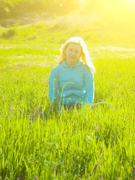 Chica sentada en un campo en la hierba verde . —  Fotos de Stock