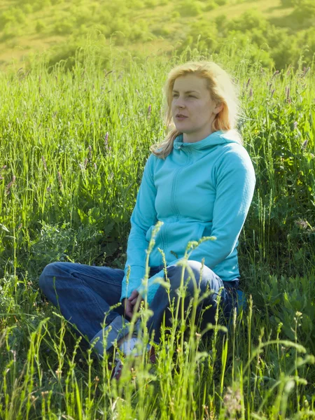 Chica sentada en un campo en la hierba verde . —  Fotos de Stock