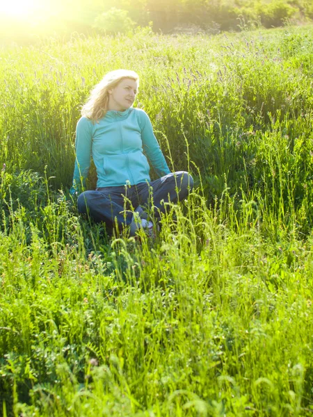 Porträtt av ung vacker flicka i en gräsbevuxen område på sunset. — Stockfoto