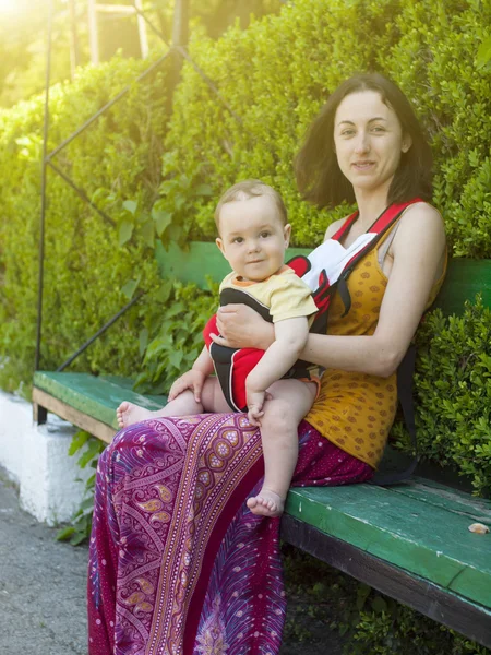 Una joven madre en vestido oriental, sosteniendo a un niño pequeño en un bebé — Foto de Stock