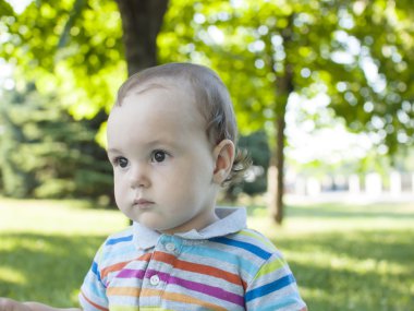 Yeşil çimenlerin üzerinde oturan üzgün çocuk .