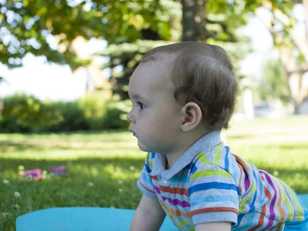 Грустный ребенок сидит на зеленой траве  . — стоковое фото