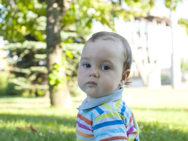 緑の草の上に座っている悲しい子供 . — ストック写真