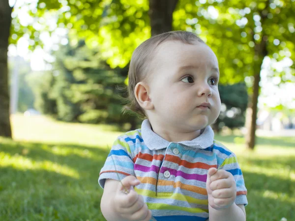 Ledsen barn sitter på det gröna gräset . — Stockfoto