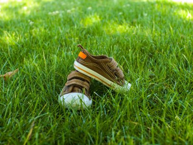 Baby sneakers are on the grass. clipart