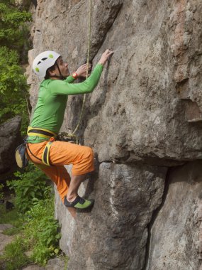 Genç dağcı zor duvara tırmanıyor.