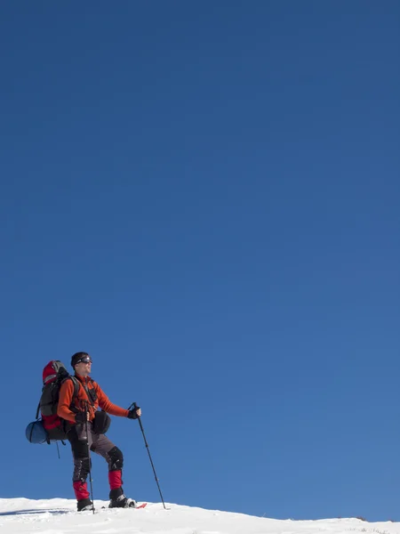 Un hombre en raquetas de nieve está en las montañas . — Foto de Stock