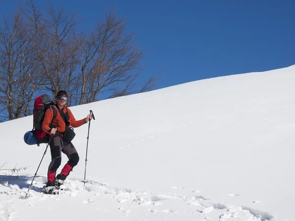 Un hombre en raquetas de nieve está en las montañas en la nieve . — Foto de Stock