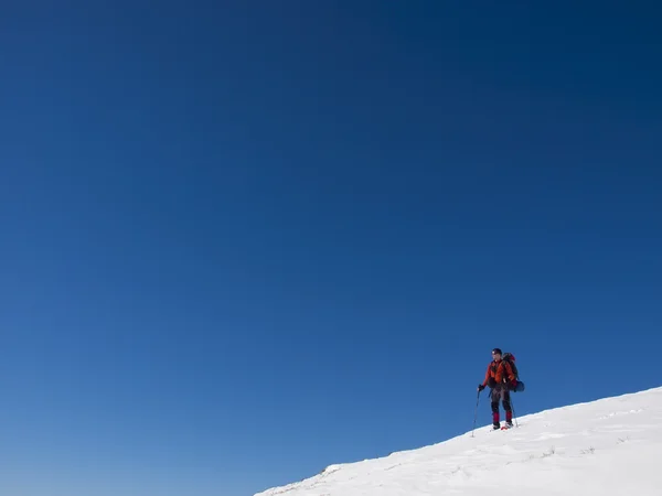 बर्फ शूजमध्ये एक माणूस डोंगरावर आहे . — स्टॉक फोटो, इमेज