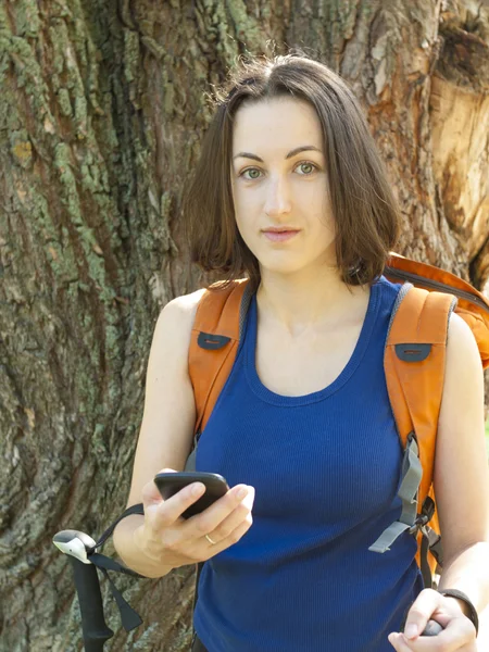 Uma jovem com uma mochila usar o telefone . — Fotografia de Stock