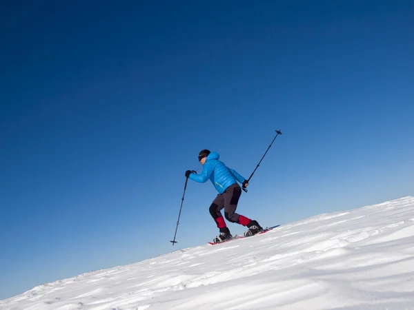 O homem salta em sapatos de neve nas montanhas . — Fotografia de Stock