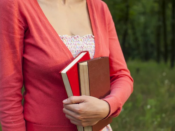 The woman is holding two books. — Stock Photo, Image