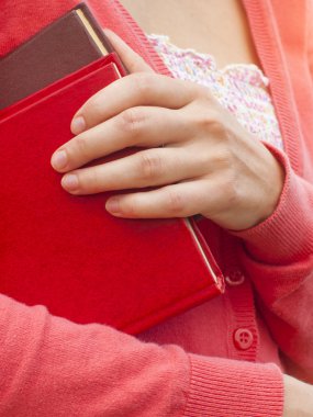 Kadın iki kitap tutuyor.