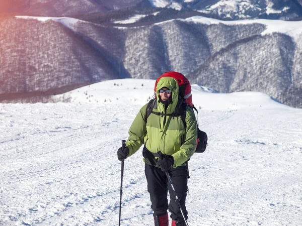 O homem com a mochila atravessa a neve . — Fotografia de Stock