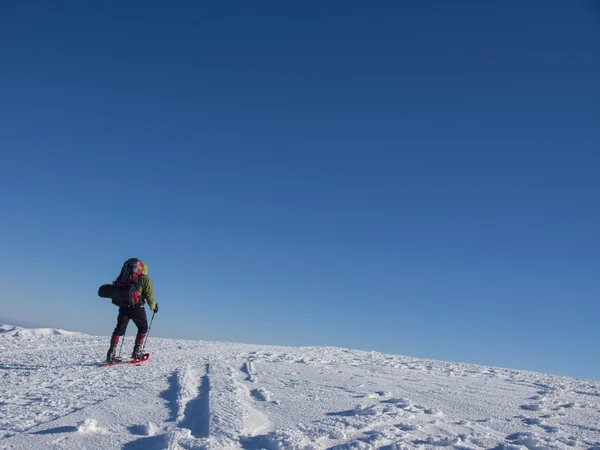 Klättraren går genom snön klädda i snöskor. — Stockfoto