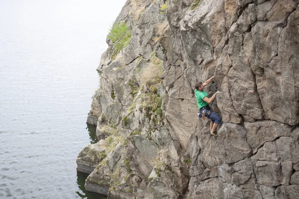 Ein Mann klettert auf den Felsen am Wasser. — Stockfoto