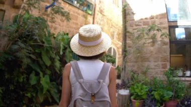 Elinde kamera olan genç bir kadın dar bir sokakta yürüyor ve fotoğraf çekiyor. Mutlu bir kız Jaffa, İsrail 'de tatilinin tadını çıkarıyor.