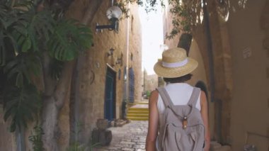 Elinde kamera olan genç bir kadın dar bir sokakta yürüyor ve fotoğraf çekiyor. Mutlu bir kız Jaffa, İsrail 'de tatilinin tadını çıkarıyor.